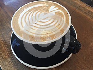 Cup of coffee in black cup with heart design