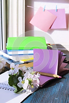 Cup of coffee, blank notebook, apple tree flowers and a stack of books, on a wooden windowsill