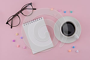 A cup of coffee, blank notebook and eyeglasses