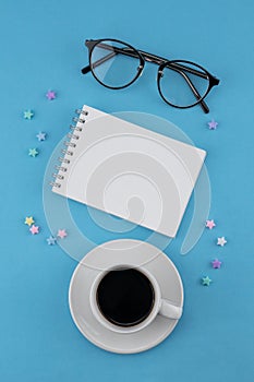 A cup of coffee, blank notebook and eyeglasses