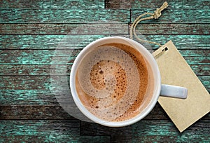 Cup of coffee and blank tag on wooden background