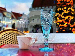 Cup of coffee , blue glass of wine on red table top ,Christmas  tree snowy holiday in Tallinn old town hall square  , winter stree