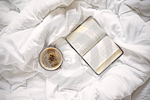 Cup of coffee and a book on bed