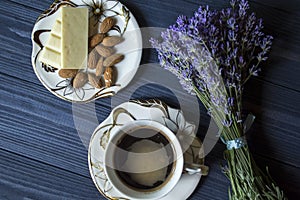 A cup of coffee, bouquet of lavender and dessert on dark blue wooden table.