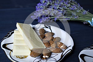 A cup of coffee, bouquet of lavender and dessert on dark blue wooden table.