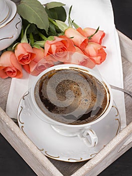 Cup of coffee and a bouquet of roses on a tray