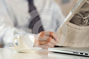 Cup of coffee with businessman reading newspaper on background