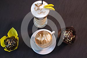 A cup of coffee in a cafe with desserts.