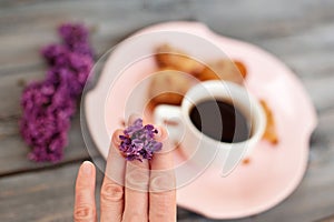 Cup of coffee, cakes and hand with a lilac branch