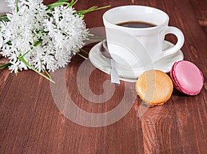 Cup coffee, cakes and white flowers