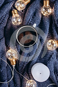 Cup of coffee , candle and warm woolen sweater , decorated with led lights.