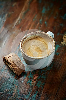 Cup of coffee with cantuccini Italian cookies on rustic wooden background.