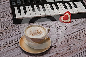 A Cup of coffee cappuccino with cinnamon and a music mixer on a wooden table.