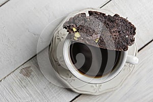 Cup of coffee with a Chocolate Biscotti or Cantuccini, on a white wooden table