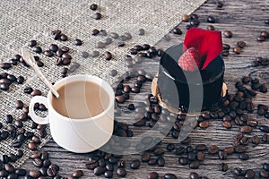 A cup of coffee with a chocolate cake with raspberries