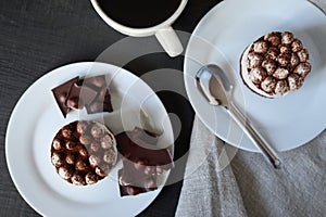 Cup of coffee and chocolate cakes on a white plate on a black background