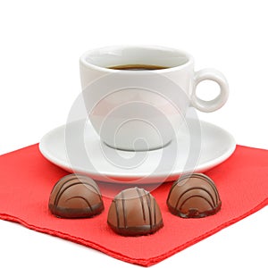 A cup of coffee and chocolate candies isolated on white background.