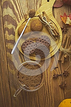 Cup of coffee, chocolate cookies and cinnamon sticks on wooden table.