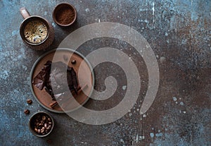 Cup of coffee, chocolate muffin and cinnamon sticks on dark stone background