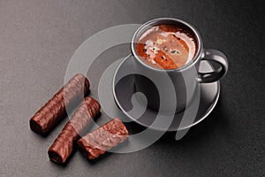 Cup of coffee and chocolates on dark background