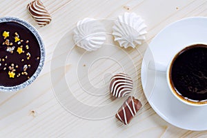 Cup of coffee, chocolates, meringue, a cottage cheese dessert of handwork on a wooden background