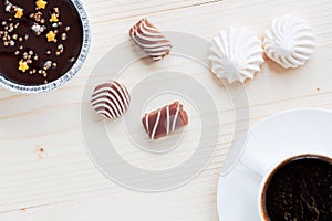 Cup of coffee, chocolates, meringue, a cottage cheese dessert of handwork on a wooden background