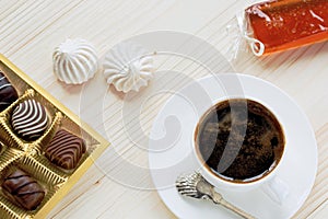 Cup of coffee, chocolates, meringue, handwork fruit jelly on a wooden background