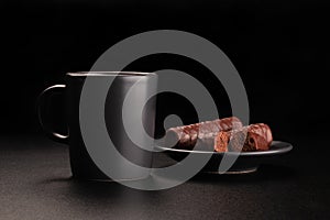 Cup of coffee and chocolates on saucer. Dark background