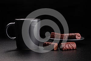 Cup of coffee and chocolates on saucer. Dark background