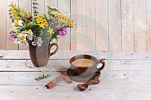 Cup of coffee with cinnamon and flowers on an old wooden table. Autumn flower arrangement, abstract background, minimal holiday
