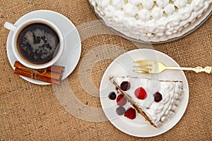 Cup of coffee, cinnamon, fork and slice of biscuit cake decorate