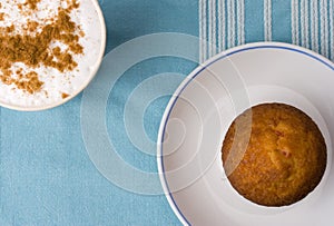 Cup of coffee with cinnamon and muffin on the plate