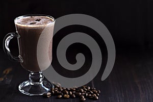 Cup of cacao. glass of hot chocolate with whipped cream, coffee beans and cinnamon sticks on a dark background.