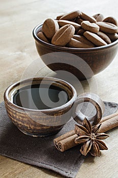 Cup coffee, cinnamon sticks and star anise with cookies on a wooden table.