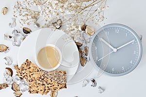 Cup of coffee and classic alarm clock on a white table. Autumn or winter cozy background. Hygge style