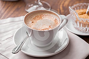 Cup of coffee close-up with spoon,  saucer and brown sugar  bowl on wooden table