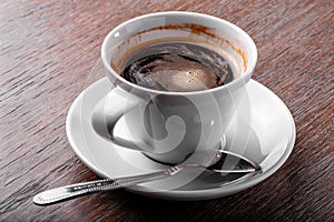 Cup of coffee close-up with spoon and saucer  on  wooden background