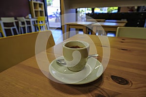 Cup of coffee close-up on the wooden table across cafe interior. Macchiato photo