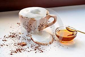 Cup of coffee cocoa with overflowing foam on dirty white background sprinkled with brown powder