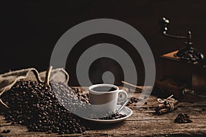 Cup of coffee with coffee beans and grinder on wooden table