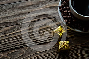 Cup of coffee, coffee beans on saucer on wooden background. Selective focus