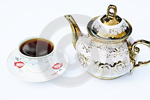A cup of coffee and beside a coffee kettle with white background.
