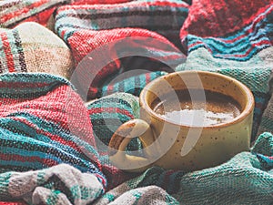 A Cup of coffee and colored textiles. Comfort on cold days. Home comfort.