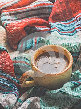 A Cup of coffee and colored textiles. Comfort on cold days. Home comfort.