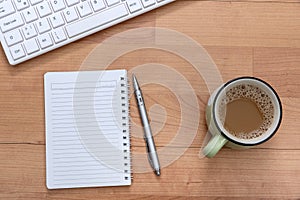 A cup of coffee, computer keyboard and ring binder on the desk