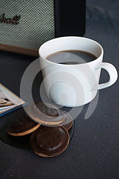 Cup with coffee, cookies with chocolate on the background of a music column on a gray table