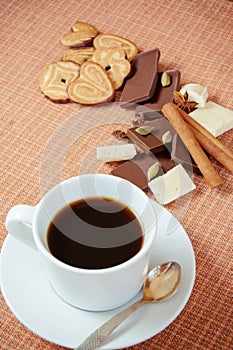 Cup of coffee with cookies, chocolate and spices on a table