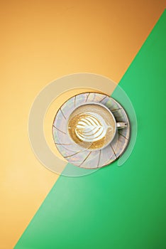 cup with coffee and cream in the form of a petal on a green-yellow background