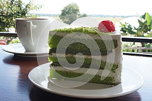 A cup of coffee and cream pandan cake on wood table