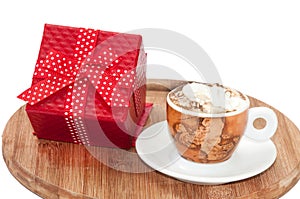 A cup of coffee with cream and red gift box with bow